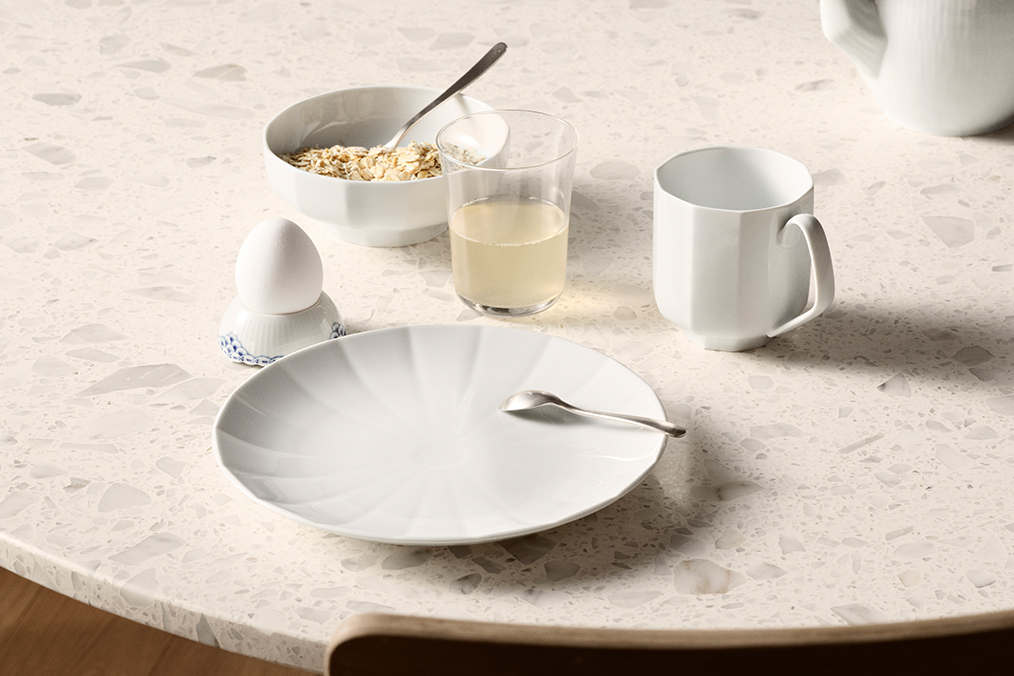 Et morgenmadsbord dækket til en person med Hvid Facet frokosttallerken, Hvid Facet skål og Hvid Facet krus.